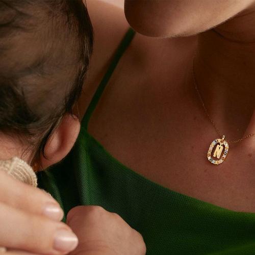 Mother holding a baby wearing an initial pendant